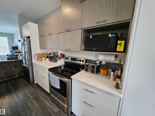 Stainless steel appliances, light wood-finish upper cabinetry, white lower cabinetry, white countertops, and a mosaic tile backsplash - 15212 98 Avenue Nw, Edmonton, AB - Indoor Photo Showing Kitchen