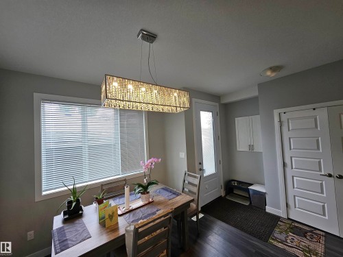 Wood-finish flooring, white paneled doors, white kitchen cabinetry, and a rectangular chandelier - 15212 98 Avenue Nw, Edmonton, AB - Indoor