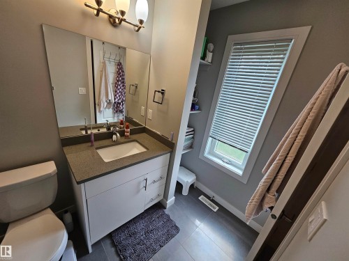 Vanity with integrated basin, brushed nickel faucet, large wall mirror, and modern lighting fixture - 15212 98 Avenue Nw, Edmonton, AB - Indoor Photo Showing Bathroom