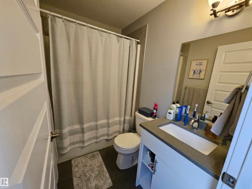 Vanity with integrated sink, stone-finish countertop, and wall-mounted light fixture - 15212 98 Avenue Nw, Edmonton, AB - Indoor Photo Showing Bathroom