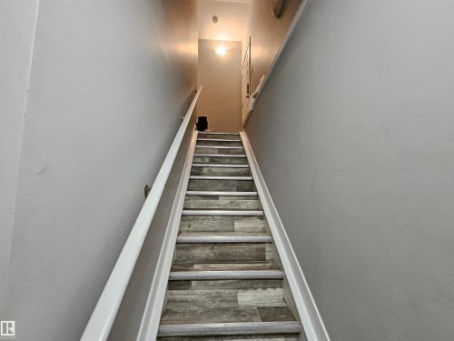 Staircase with wood-finish risers and treads, featuring a white handrail and light gray wall paint - 15212 98 Avenue Nw, Edmonton, AB - Indoor Photo Showing Other Room