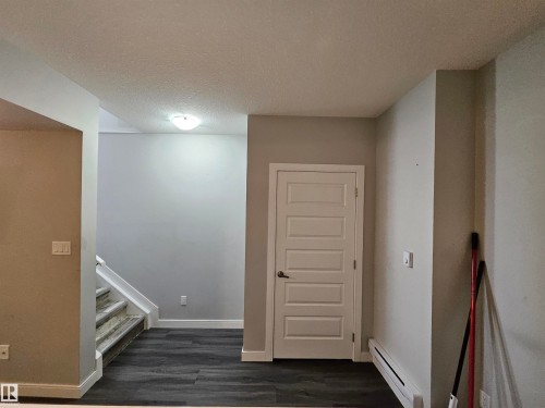 Wood-finish flooring, white paneled door, flush-mount ceiling light, and light gray wall paint - 15212 98 Avenue Nw, Edmonton, AB - Indoor Photo Showing Other Room