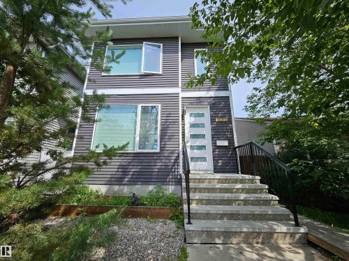 Modern facade with dark horizontal siding, white trim, and a prominent white entry door - 15212 98 Avenue Nw, Edmonton, AB - Outdoor