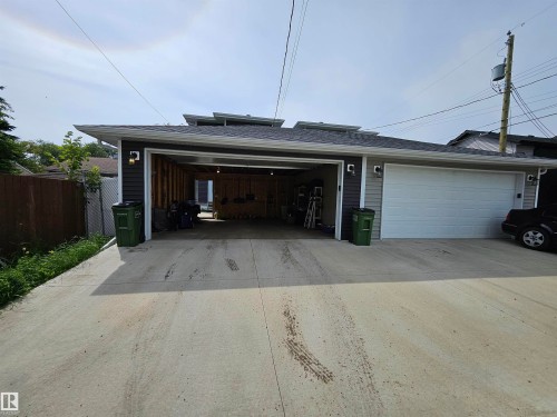 Detached garage with gray siding, a white sectional garage door, and exterior wall sconces - 15212 98 Avenue Nw, Edmonton, AB - Outdoor