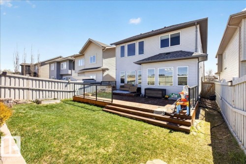 Expansive backyard featuring a manicured lawn, a multi-level wood deck with glass panel railing, and a vinyl-sided exterior with multiple windows - 3936 Claxton Loop Sw, Edmonton, AB - Outdoor With Deck Patio Veranda With Exterior