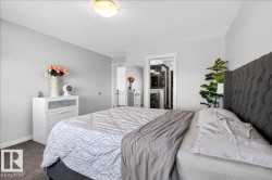 Spacious primary bedroom featuring a charcoal tufted upholstered headboard, carpeted flooring, and abundant natural light from recessed ceiling fixtures - 