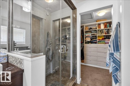 Glass-enclosed shower with tiled walls and flooring, rainfall showerhead, and multi-function shower system - 3936 Claxton Loop Sw, Edmonton, AB - Indoor