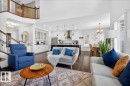 Open-concept living area featuring wood-finish flooring, a two-story entryway, and a prominent staircase with wood and metal railing - 3936 Claxton Loop Sw, Edmonton, AB  - Indoor Photo Showing Living Room 