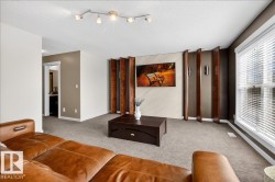Spacious living room featuring polished concrete flooring, track lighting with multiple fixtures, and floor-to-ceiling windows with integrated blinds - 