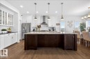 Kitchen featuring wood-finish flooring, a central island with a sink, white cabinetry with glass-front uppers, stainless steel appliances, and recessed lighting - 3936 Claxton Loop Sw, Edmonton, AB  - Indoor Photo Showing Kitchen With Upgraded Kitchen 