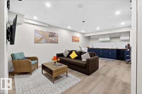 Finished basement recreation room featuring plank wood-finish flooring, recessed ceiling lighting, and wall-mounted flat-screen television - 3936 Claxton Loop Sw, Edmonton, AB - Indoor