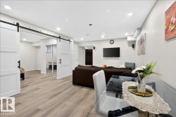 Spacious lower level featuring wood-finish flooring, recessed lighting, and white barn doors with black hardware - 