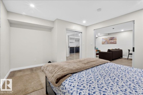 Recessed lighting, wood-finish flooring, sliding glass closet doors, open doorway, and neutral wall tones - 3936 Claxton Loop Sw, Edmonton, AB - Indoor Photo Showing Bedroom