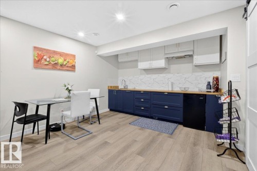 Modern kitchen featuring custom navy cabinetry with brushed metal hardware, white marble subway tile backsplash, and stainless steel appliances - 3936 Claxton Loop Sw, Edmonton, AB - Indoor
