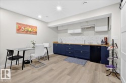 Modern kitchen featuring custom navy cabinetry with brushed metal hardware, white marble subway tile backsplash, and stainless steel appliances - 