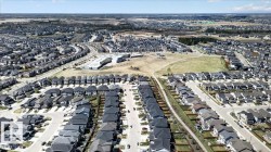 Residential development with numerous detached homes, paved streets, and open green spaces - 