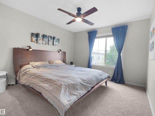 Carpeted room featuring a ceiling fan, a large window, and light-toned walls - #89 603 Watt Bv Sw, Edmonton, AB - Indoor Photo Showing Bedroom