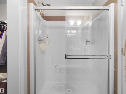 Shower enclosure with clear glass sliding door, chrome hardware, and tiled surround - #89 603 Watt Bv Sw, Edmonton, AB - Indoor Photo Showing Bathroom