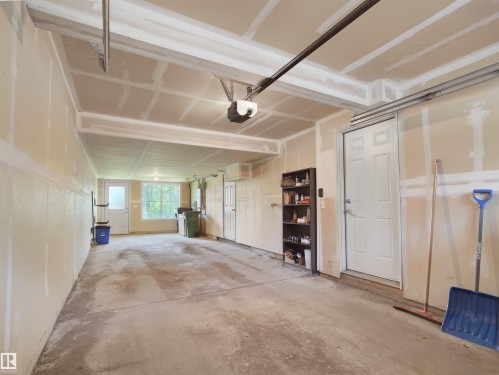 Spacious garage with concrete flooring, multiple windows, and exterior door access - #89 603 Watt Bv Sw, Edmonton, AB - Indoor