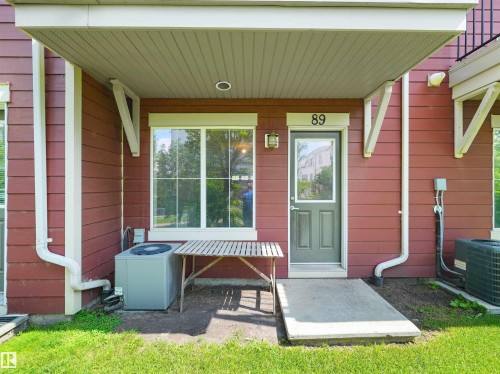 Red horizontal siding with white trim, covered patio, and a concrete pathway - #89 603 Watt Bv Sw, Edmonton, AB - Outdoor With Exterior