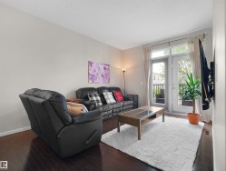 Dark wood-finish flooring, light neutral wall tones, and double French doors opening to an exterior balcony with black iron railings - 