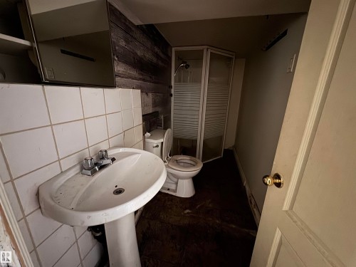 White pedestal sink with chrome faucet, white tiled wall, and wood-paneled accent wall - 11147 97 Street Nw, Edmonton, AB - Indoor Photo Showing Bathroom