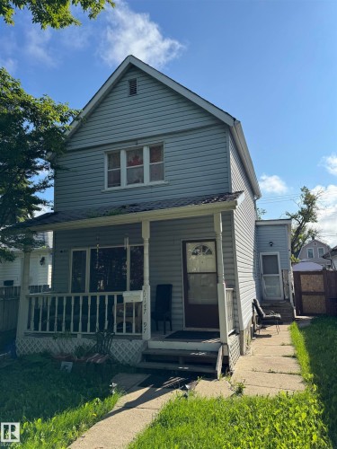 Two-story home featuring horizontal siding exterior, pitched roofline with gable detailing, front-facing covered porch with railings, and multi-pane windows across the facade - 11147 97 Street Nw, Edmonton, AB - Outdoor