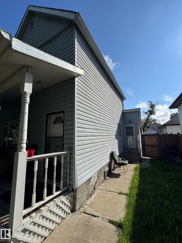 Charming cottage-style home featuring horizontal vinyl siding, a gabled roofline with dark trim, and a covered front porch with white railings and metal steps - 11147 97 Street Nw, Edmonton, AB - Outdoor With Exterior
