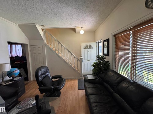 Entryway featuring a white paneled door with an arched glass insert, wood-finish flooring, and a staircase with white balusters - 11147 97 Street Nw, Edmonton, AB - Indoor