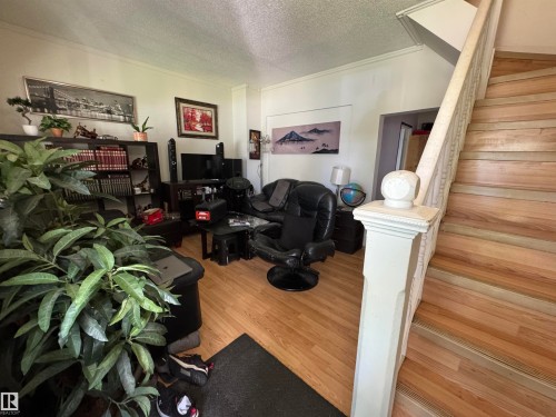 Wood-finish flooring with a traditional staircase featuring a carved newel post and balusters - 11147 97 Street Nw, Edmonton, AB - Indoor Photo Showing Other Room