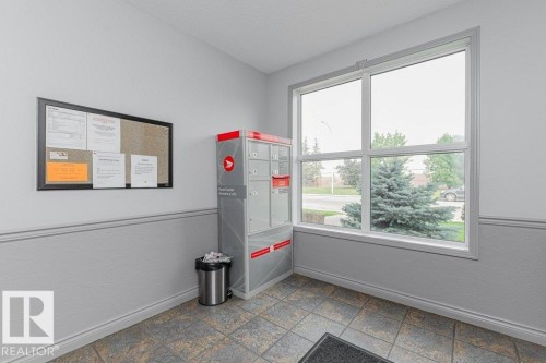 Bright corner office featuring large dual-pane windows with expansive natural light, neutral two-tone wall treatment with chair rail molding, tile flooring, and built-in bulletin board for organization - #208 10421 42 Av Nw, Edmonton, AB - Indoor Photo Showing Other Room