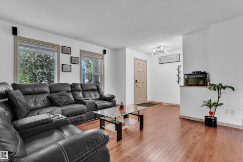 Living area featuring wood-finish flooring, white walls, and multiple windows - 7223 19A Avenue Sw, Edmonton, AB - Indoor Photo Showing Living Room With Fireplace
