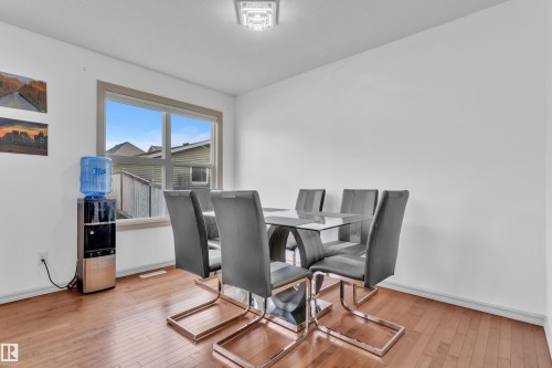 Bright room featuring wood-finish flooring, a large window with white trim, and a flush-mount ceiling light fixture - 7223 19A Avenue Sw, Edmonton, AB - Indoor Photo Showing Dining Room