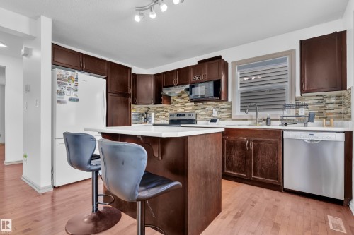 Kitchen featuring wood-finish flooring, dark wood cabinetry, and white countertops - 7223 19A Avenue Sw, Edmonton, AB - Indoor Photo Showing Kitchen