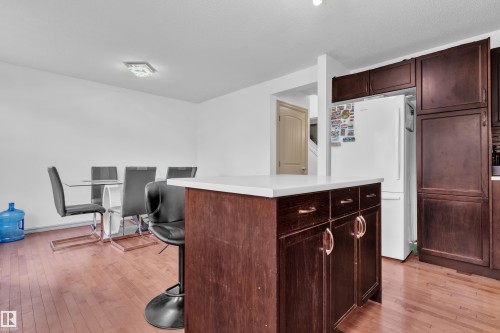 Kitchen island featuring a white countertop and dark wood-finish cabinetry - 7223 19A Avenue Sw, Edmonton, AB - Indoor