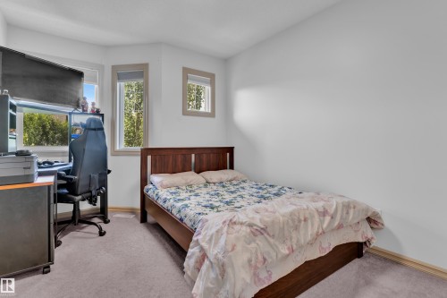 Bedroom featuring a wood-finish bed frame, light gray carpeting, and multiple windows with trim - 7223 19A Avenue Sw, Edmonton, AB - Indoor Photo Showing Bedroom