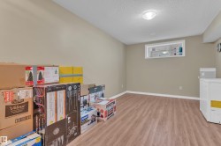 Spacious lower-level room featuring wood-finish flooring, neutral wall paint, and white baseboards - 