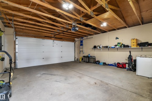 Spacious two-car garage featuring a concrete floor, exposed wood beam ceiling, and a white panel garage door - 7223 19A Avenue Sw, Edmonton, AB - Indoor Photo Showing Garage