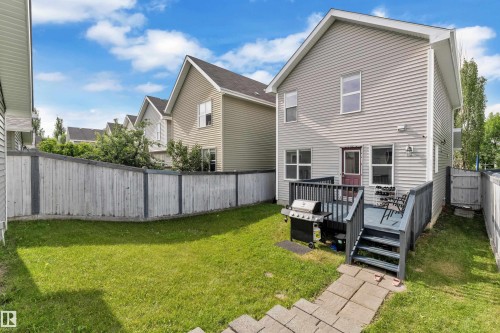 Private backyard featuring a gray wooden deck with steps, a stone paver pathway, and a perimeter wooden fence - 7223 19A Avenue Sw, Edmonton, AB - Outdoor With Deck Patio Veranda