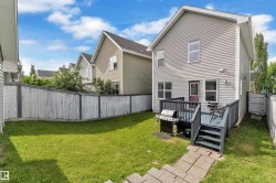 Private backyard featuring a gray wooden deck with steps, a stone paver pathway, and a perimeter wooden fence - 