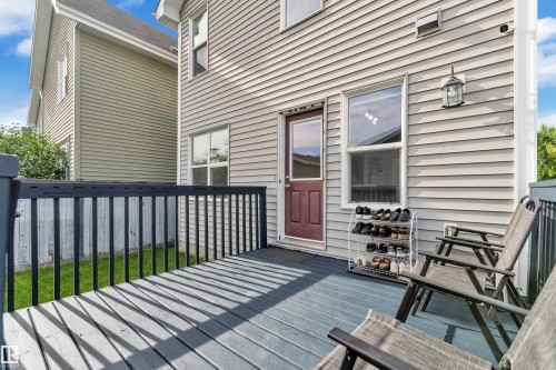 Outdoor deck featuring a dark blue wood-finish surface, black railings, and a red exterior door with a window panel - 7223 19A Avenue Sw, Edmonton, AB - Outdoor With Deck Patio Veranda
