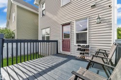 Outdoor deck featuring a dark blue wood-finish surface, black railings, and a red exterior door with a window panel - 