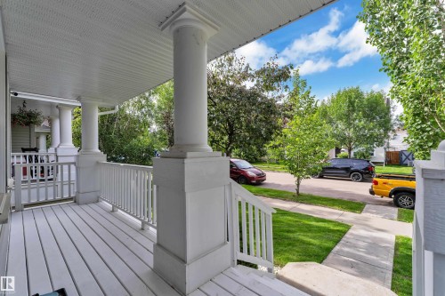 Covered front porch featuring white decking, classic balusters, and substantial support columns - 7223 19A Avenue Sw, Edmonton, AB - Outdoor With Deck Patio Veranda With Exterior