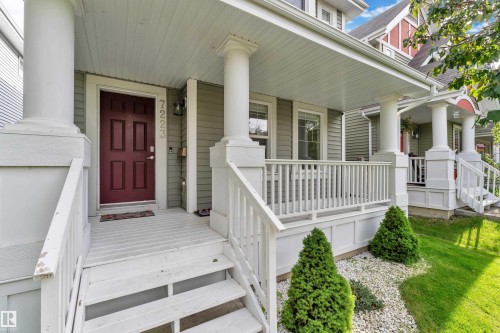 Covered front porch with white railing and columns, featuring a deep red paneled door - 7223 19A Avenue Sw, Edmonton, AB - Outdoor With Deck Patio Veranda With Facade