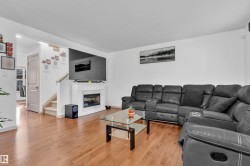 Living area featuring wood-finish flooring, a white-mantled fireplace, and a partial staircase with carpeted treads - 