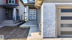 Contemporary exterior featuring light gray siding with white stacked stone accents - 