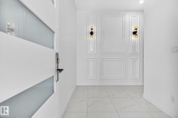 Modern entry featuring a white door with frosted glass panels and a contemporary handle - 