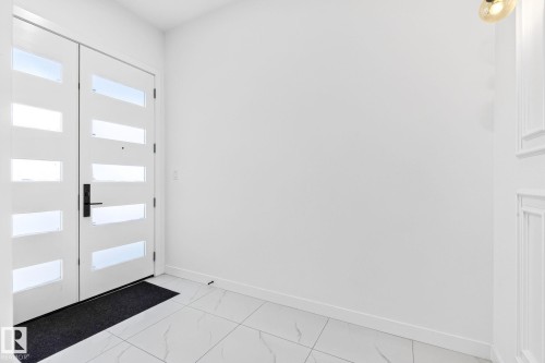 Contemporary entryway featuring double doors with frosted glass panels, black hardware, and white baseboards - 3926 41 Avenue, Beaumont, AB - Indoor Photo Showing Other Room