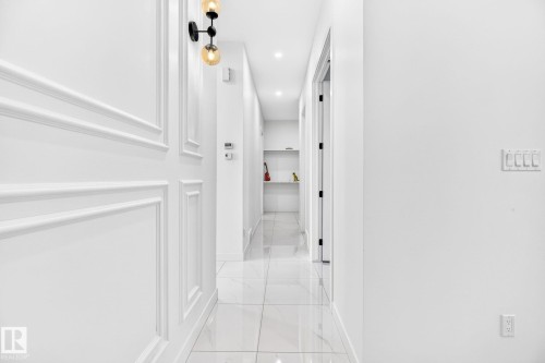 Hallway featuring white wainscoting, polished tile flooring, recessed lighting, and a modern sconce fixture - 3926 41 Avenue, Beaumont, AB - Indoor Photo Showing Other Room