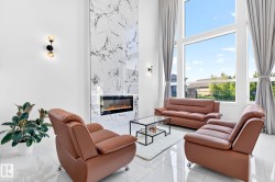Two-story living area featuring a full-height marble-look fireplace surround, an integrated electric fireplace, and expansive floor-to-ceiling windows - 